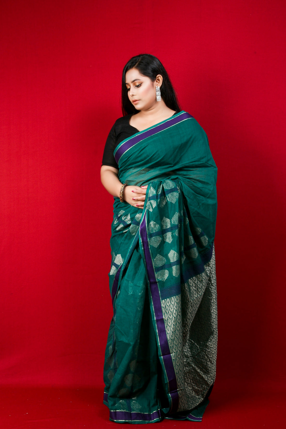 woman in green and blue sari standing beside red wall