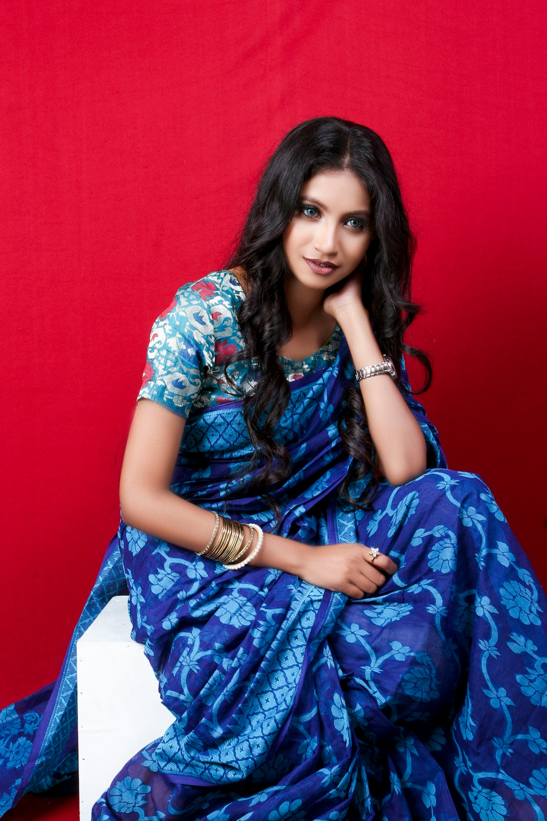woman in blue and white floral dress sitting on white textile