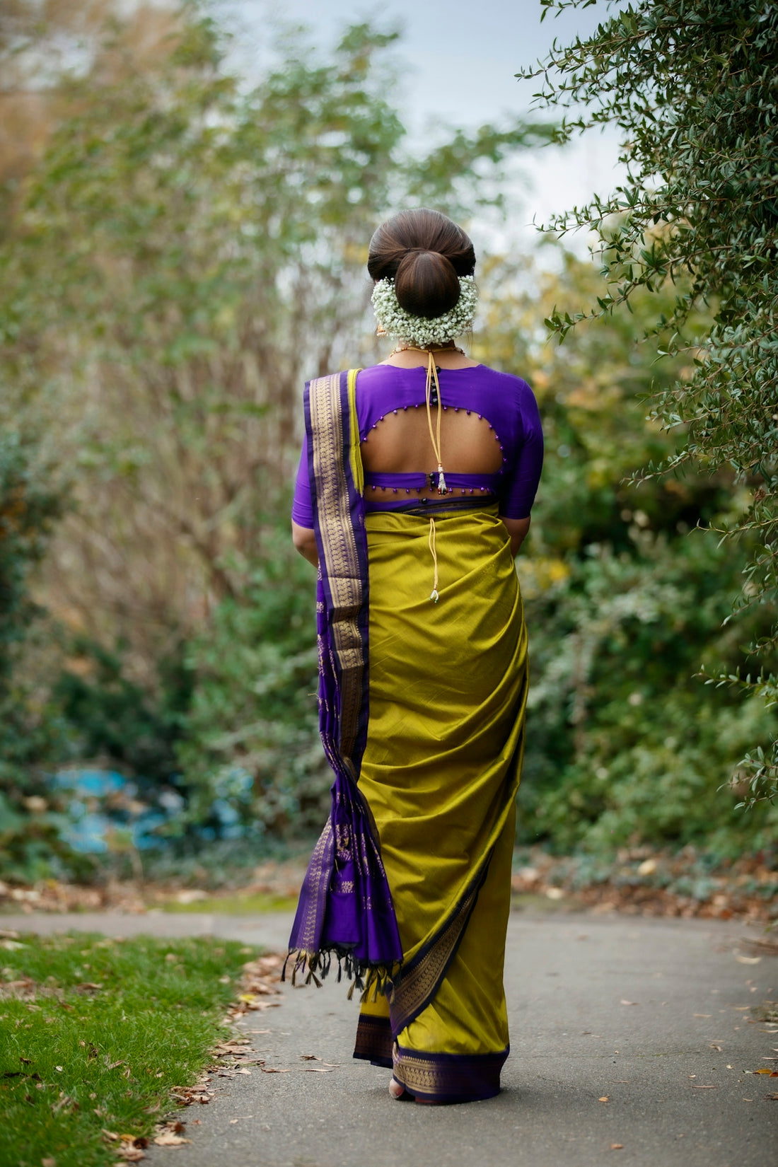 woman in yellow and purple sari standing on road during daytime