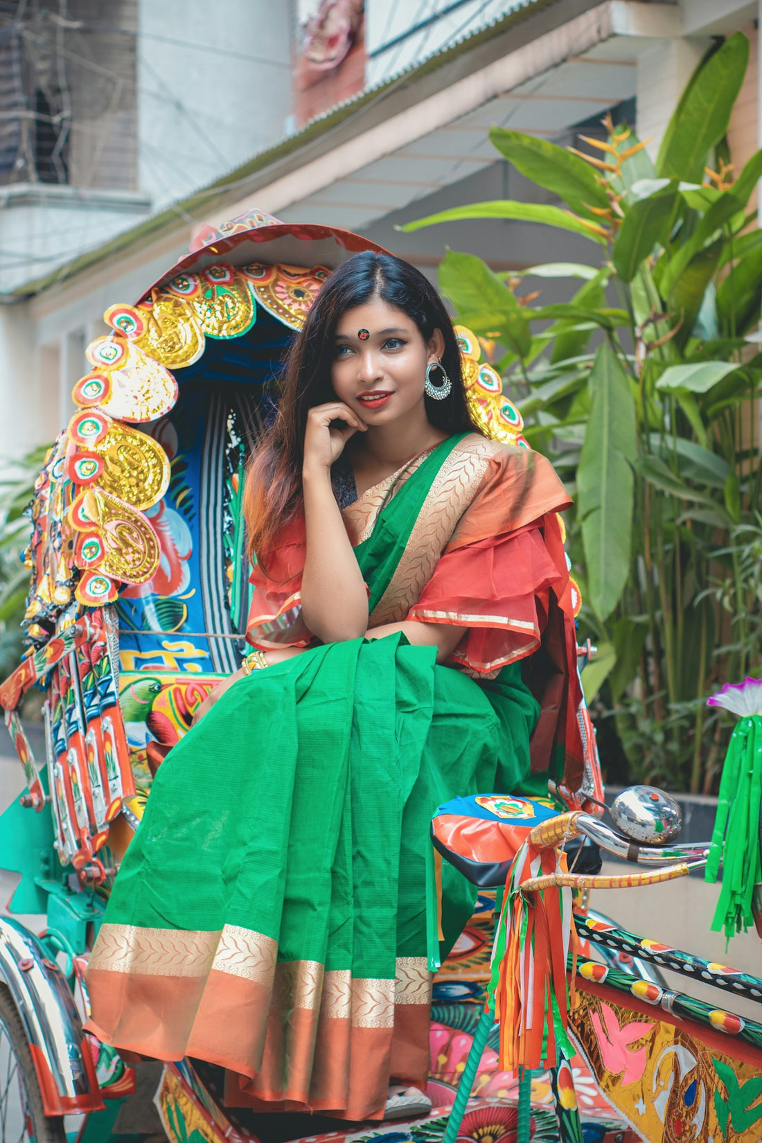 a woman in a green and orange sari sitting on a horse drawn carriage