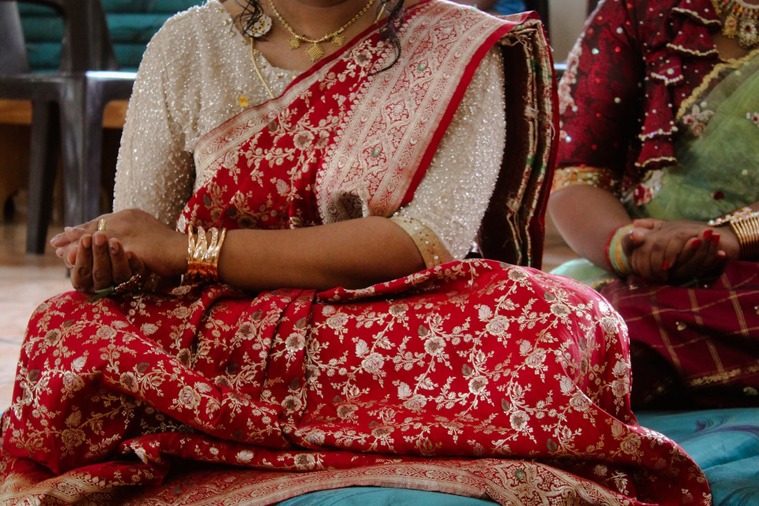 a woman in a red and white sari sitting on a bed
