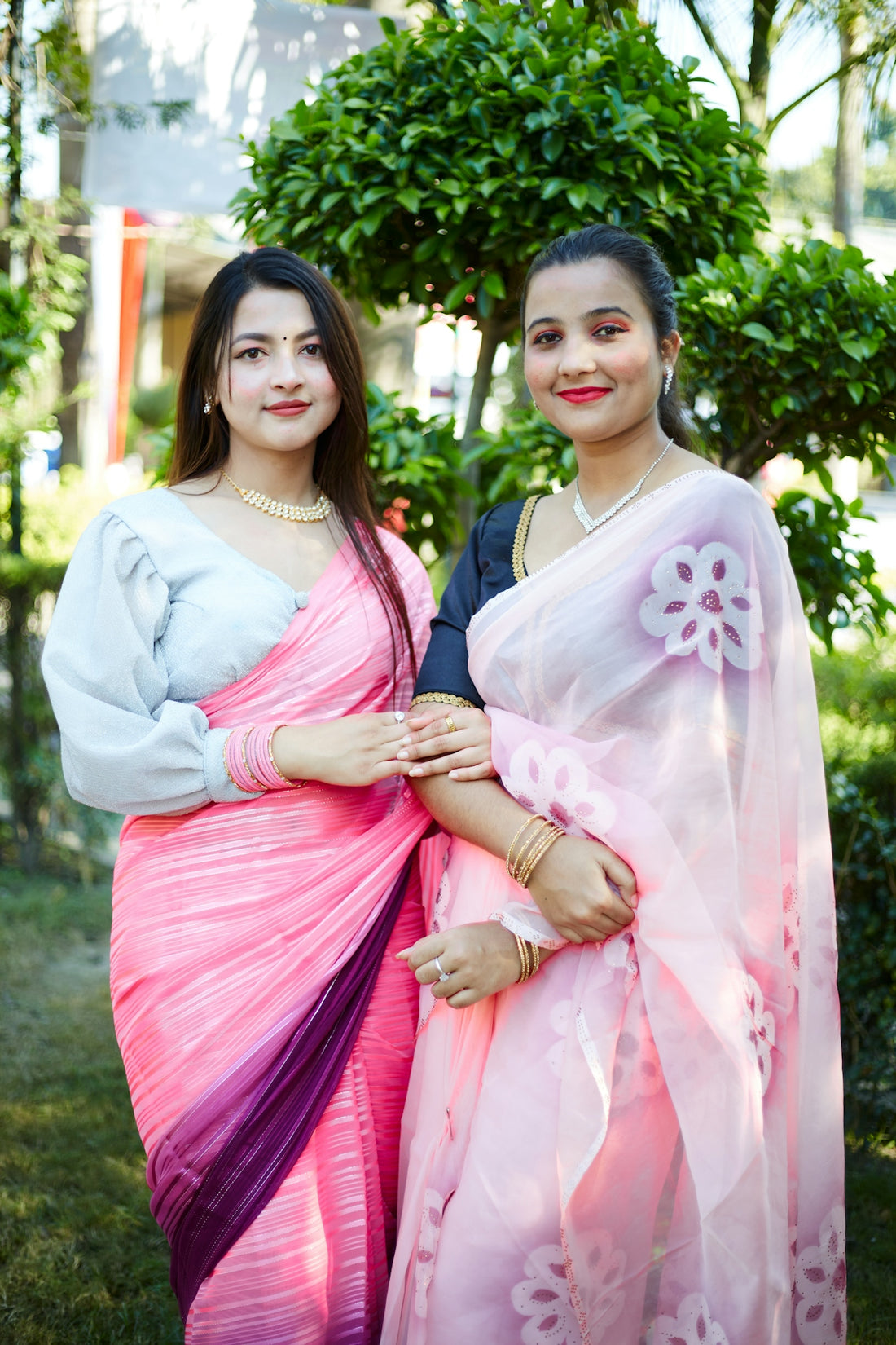 two women standing next to each other in a park