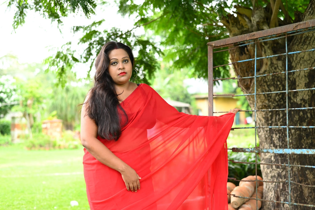 a woman in a red sari standing next to a tree