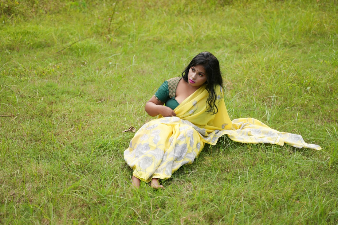 a woman in a yellow sari sitting in the grass