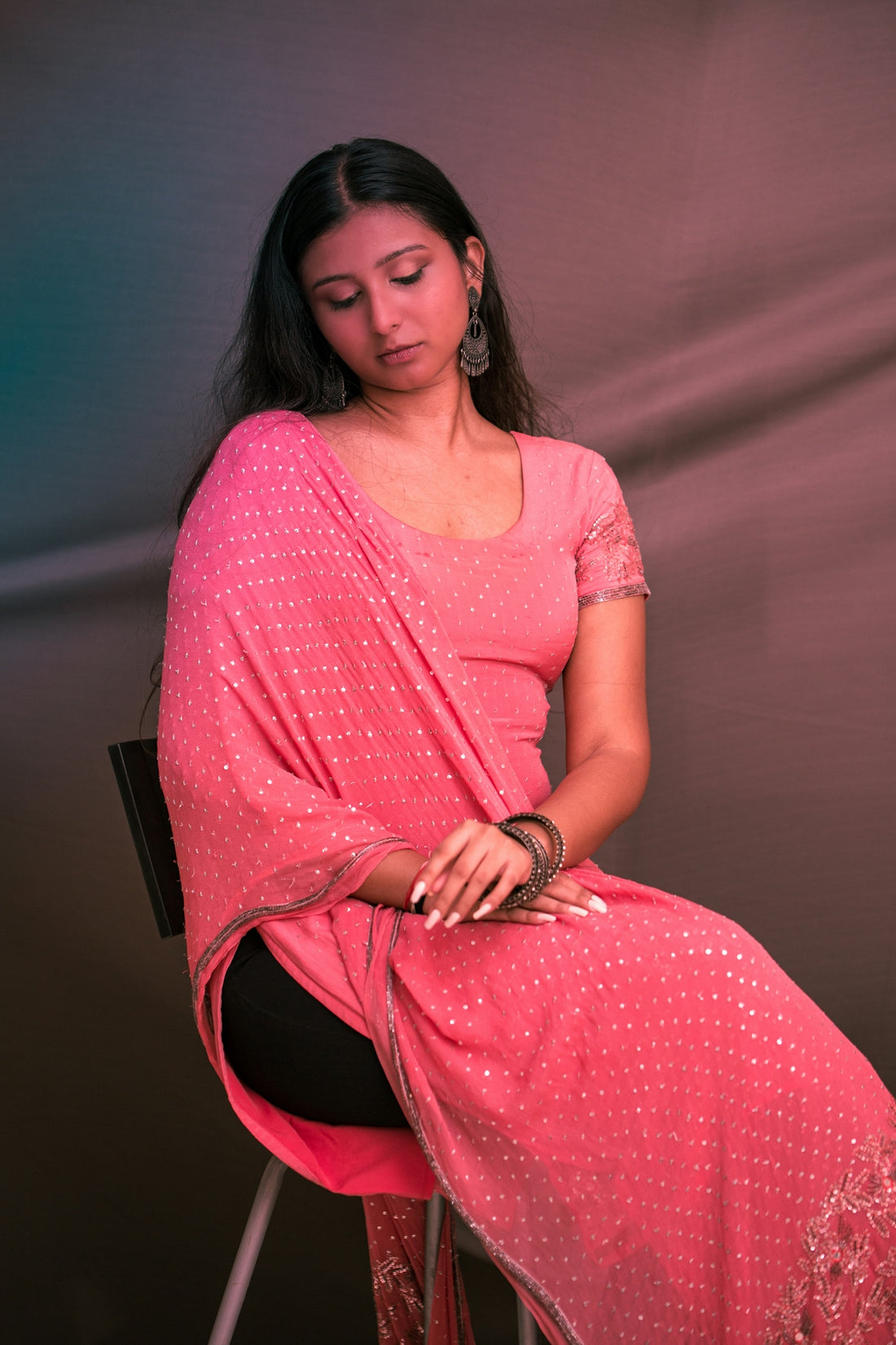 A woman in a pink sari sitting on a chair