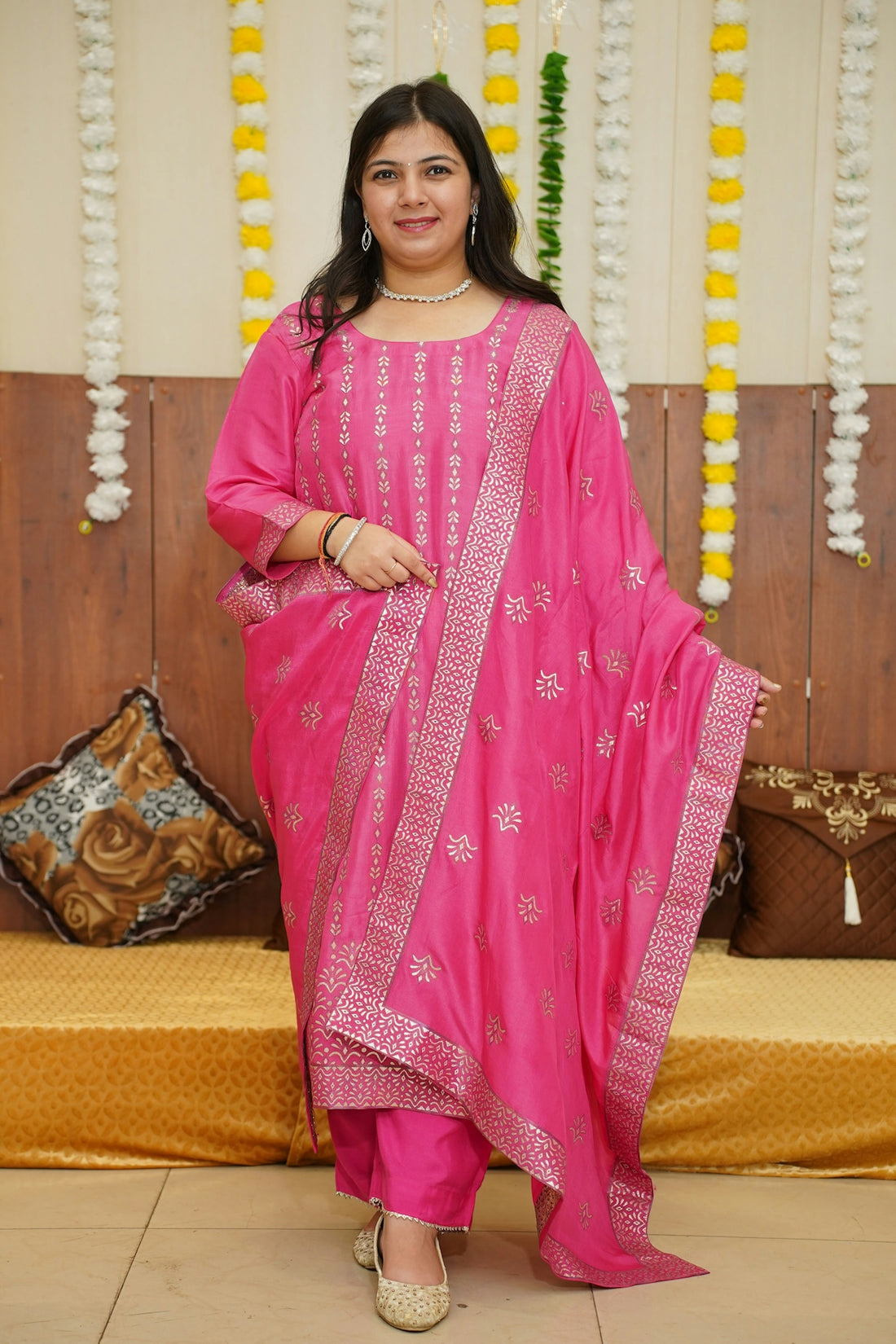 A woman in a pink outfit standing in front of a bed
