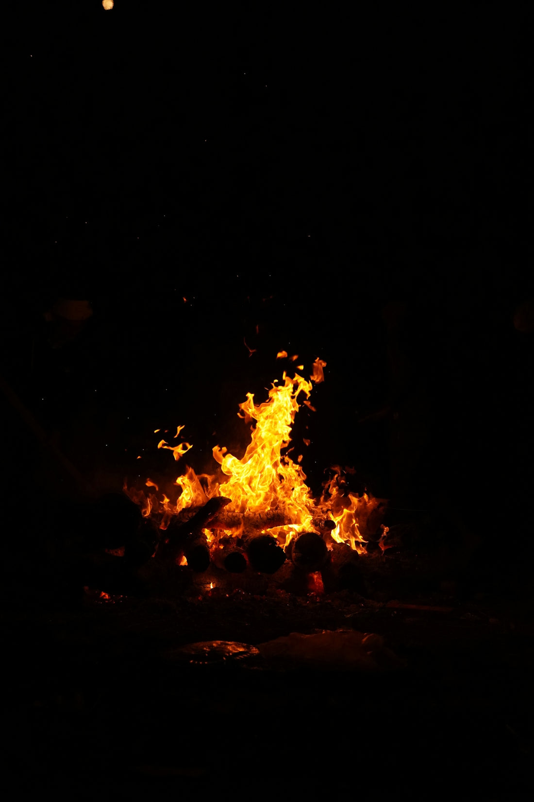 A fire is lit in the dark with bright orange flames