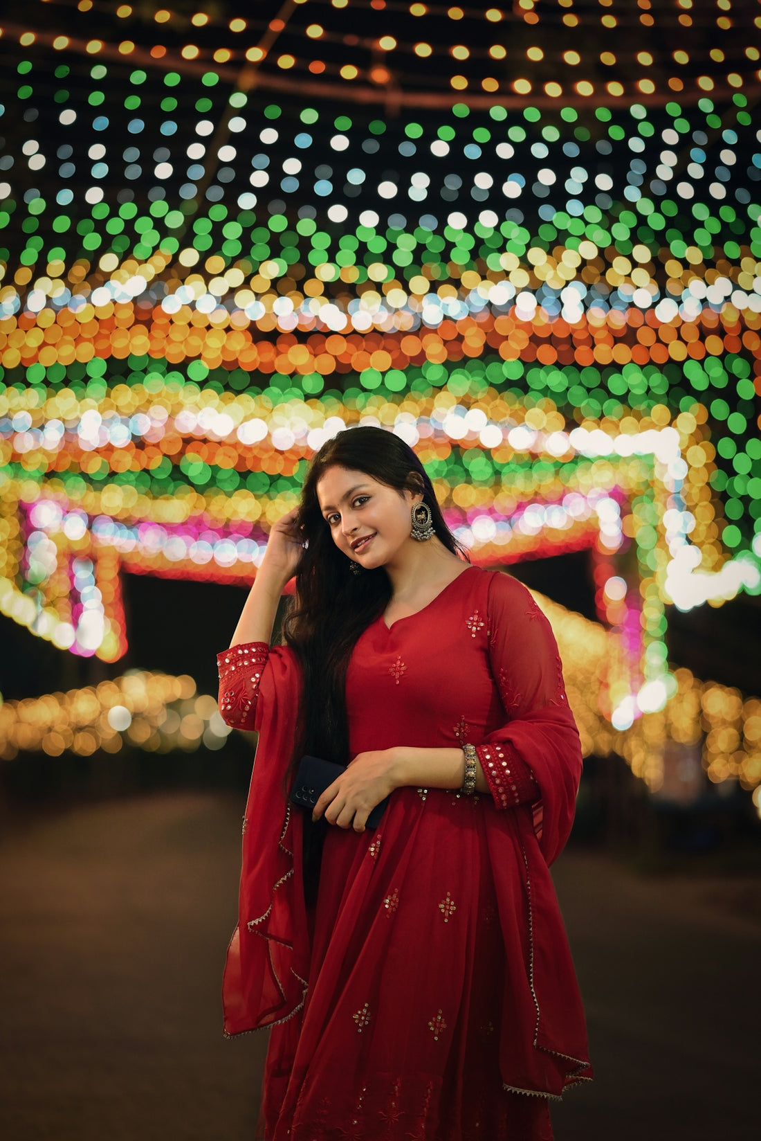 A woman in a red dress standing in front of lights