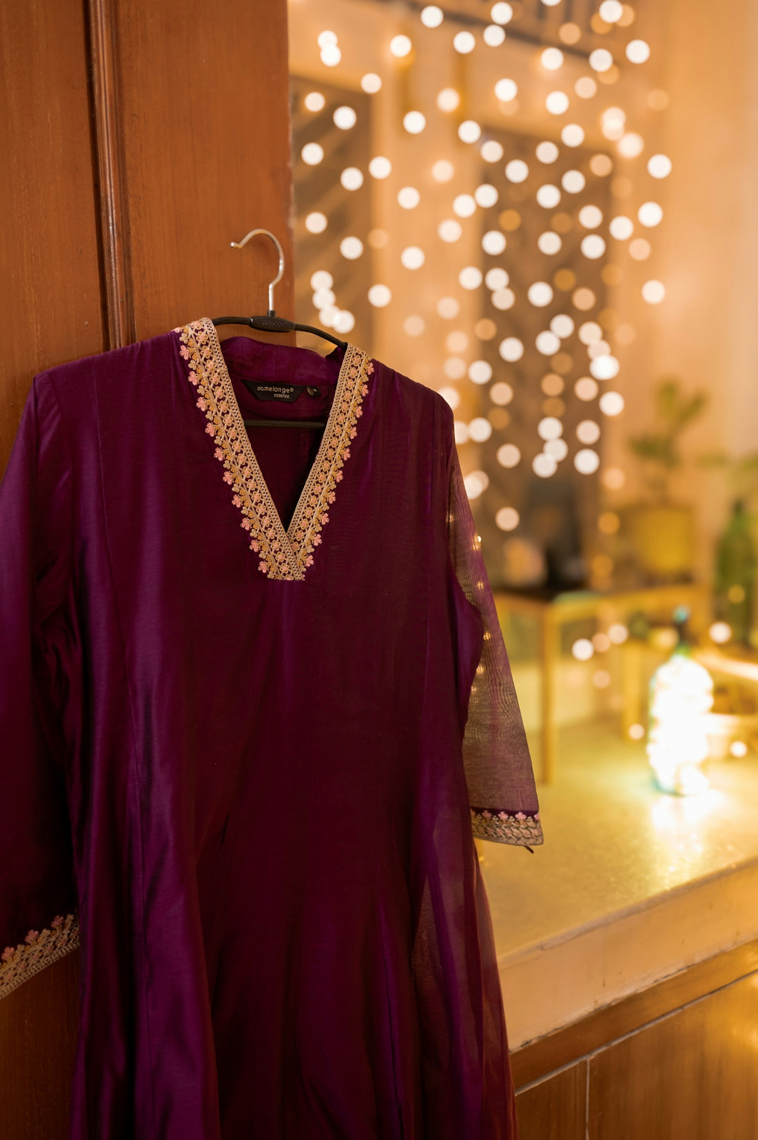 A dress hanging on a door with lights in the background