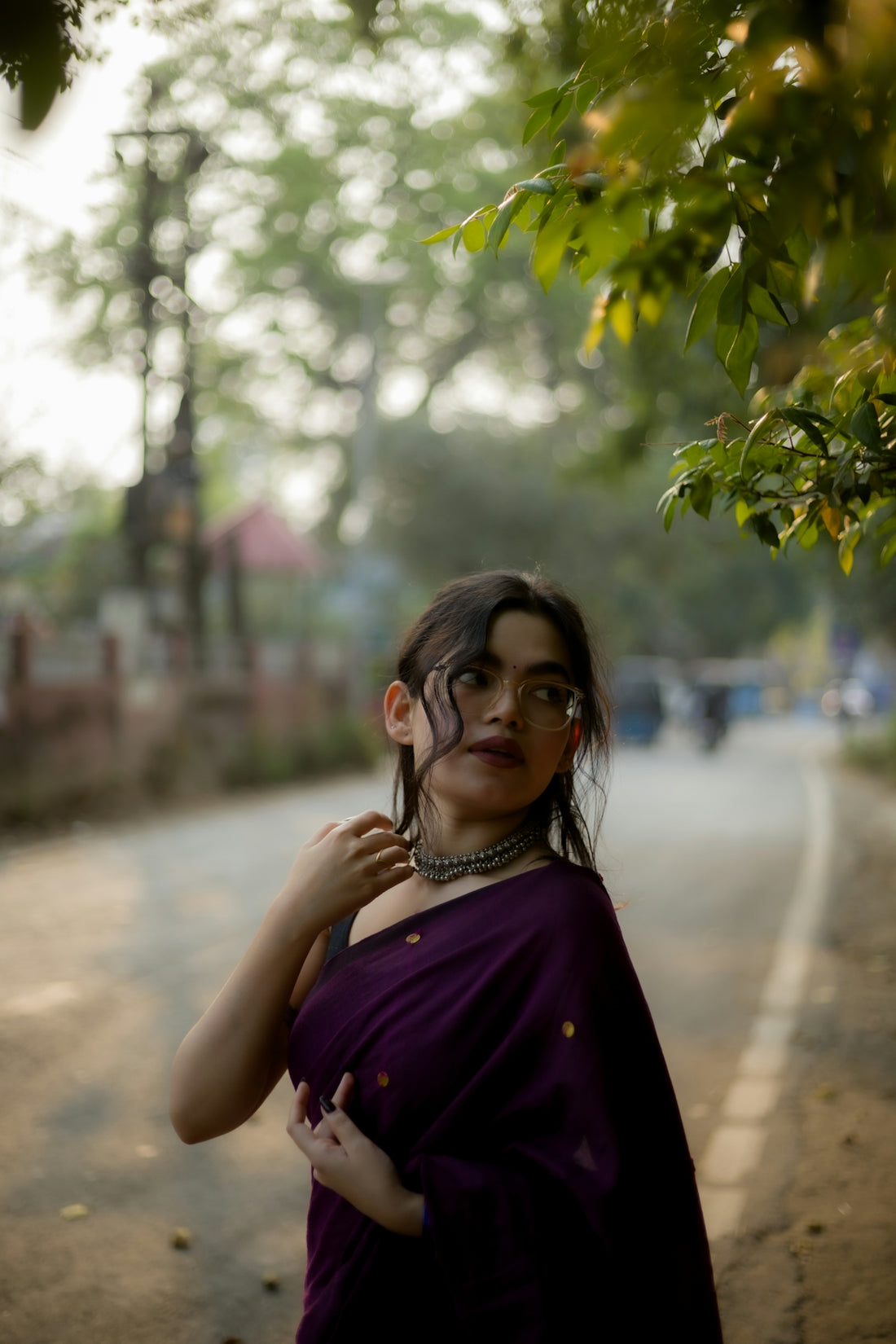Woman in a saree poses on a road.