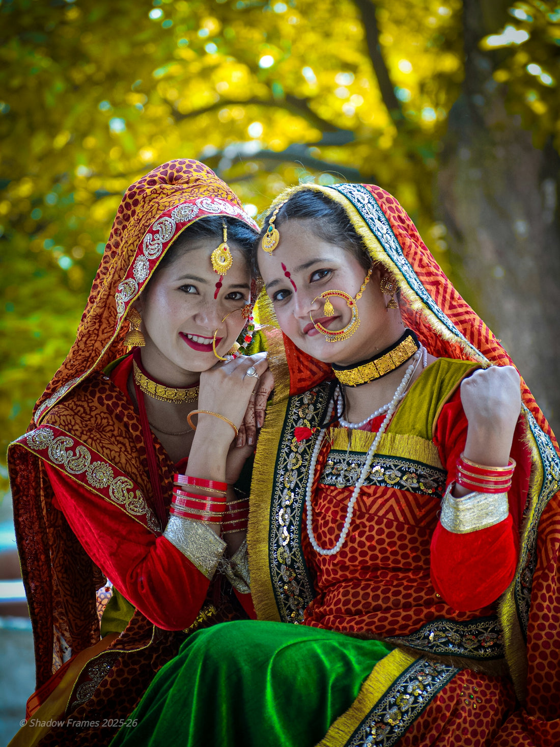 Two women in traditional indian wedding attire smile.