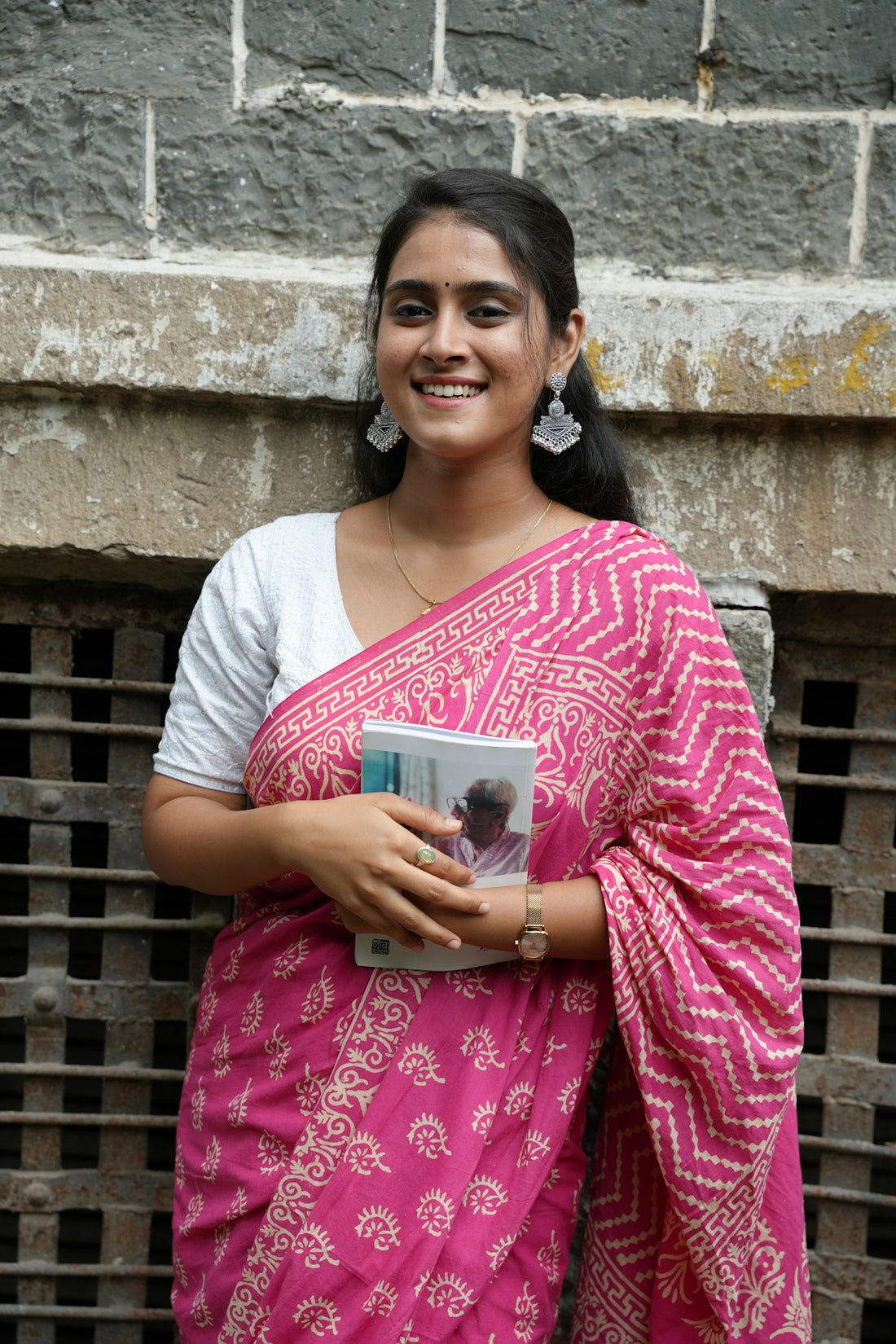 A woman in a sari holds a book.