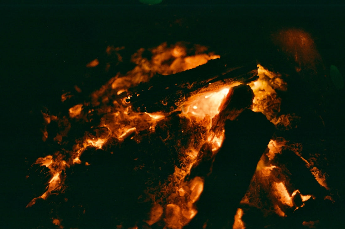 A person silhouetted near a glowing bonfire.