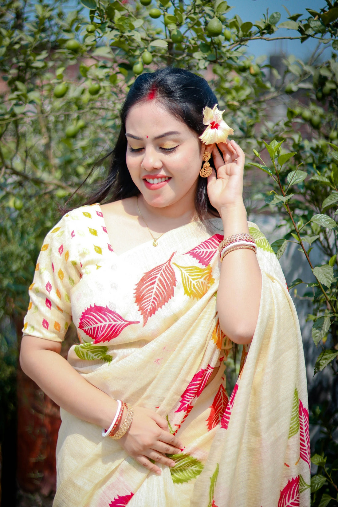 A woman smiles while wearing a floral saree.